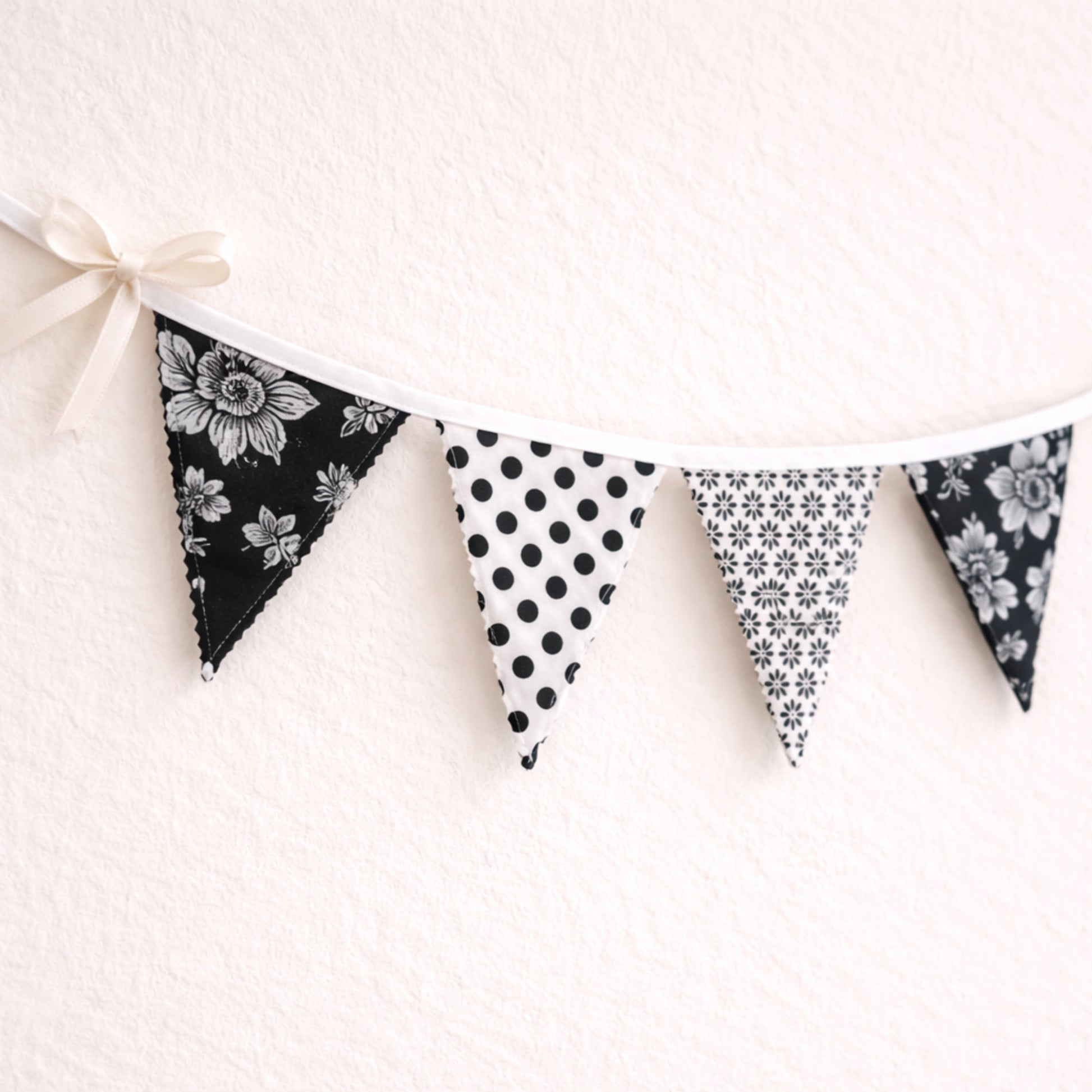 Close up of black and white fabric bunting banner showing scalloped zig-zag flag edges and cotton bias binding handmade nursery decor