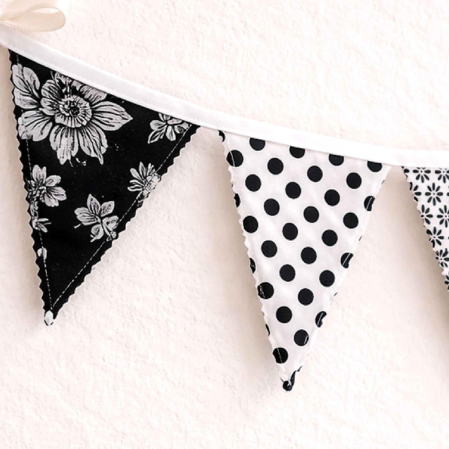 Close up of black white floral fabric bunting banner showing zig zag stitched edge and cotton binding detail