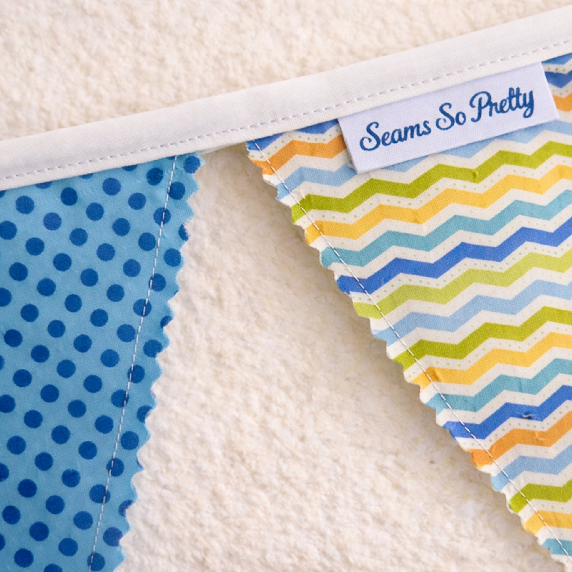 Close up of blue bunting banner showing zig zag stitched fabric flags and cotton bias binding