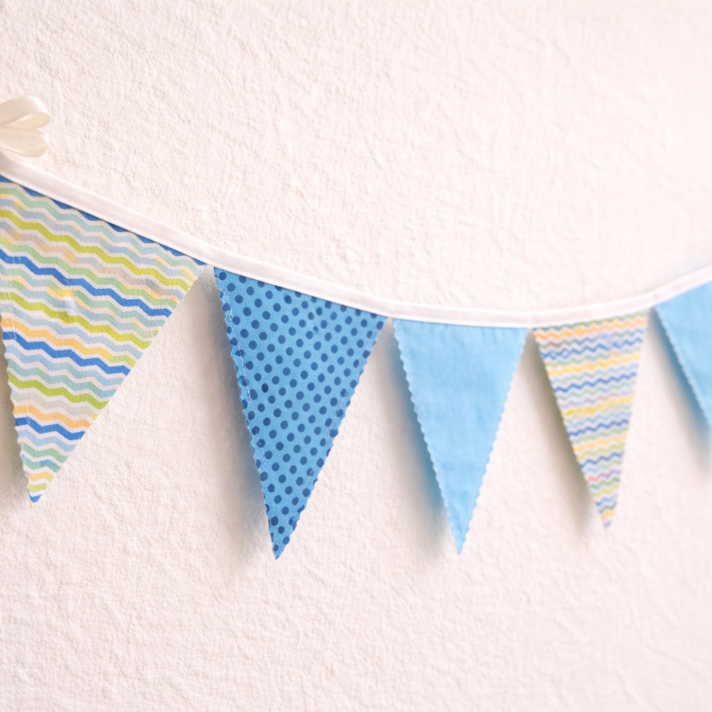 Blue nursery bunting banner with fabric flags and cotton bias binding hanging on nursery wall