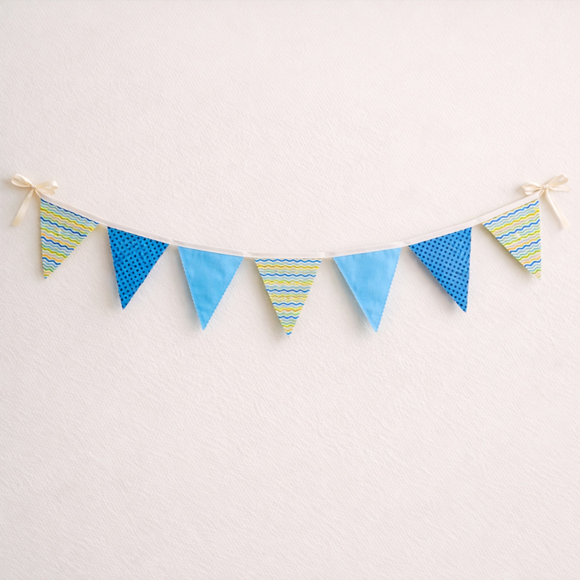 Blue fabric bunting banner with zig zag stitched flags and cotton bias binding for baby nursery decor