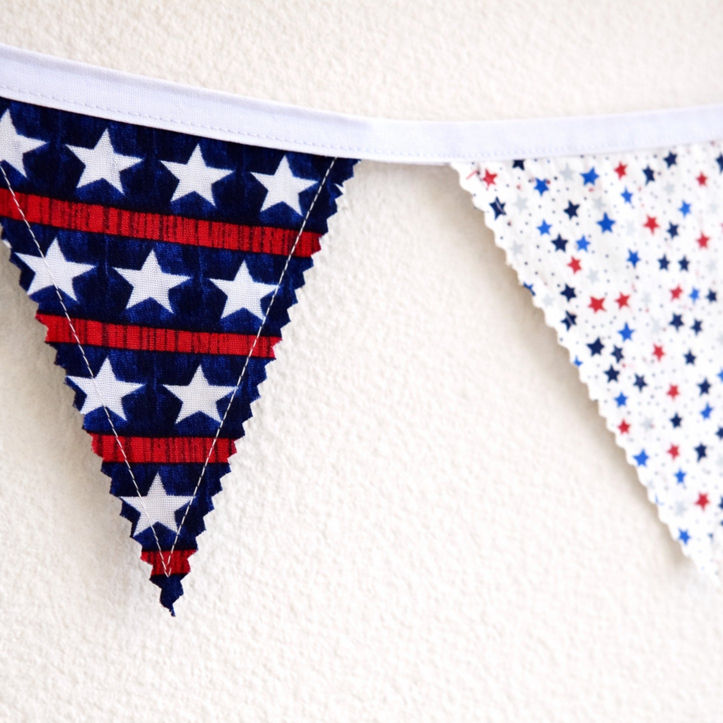 Close up of patriotic bunting banner showing zig zag pinked fabric edges and star print flags with white binding