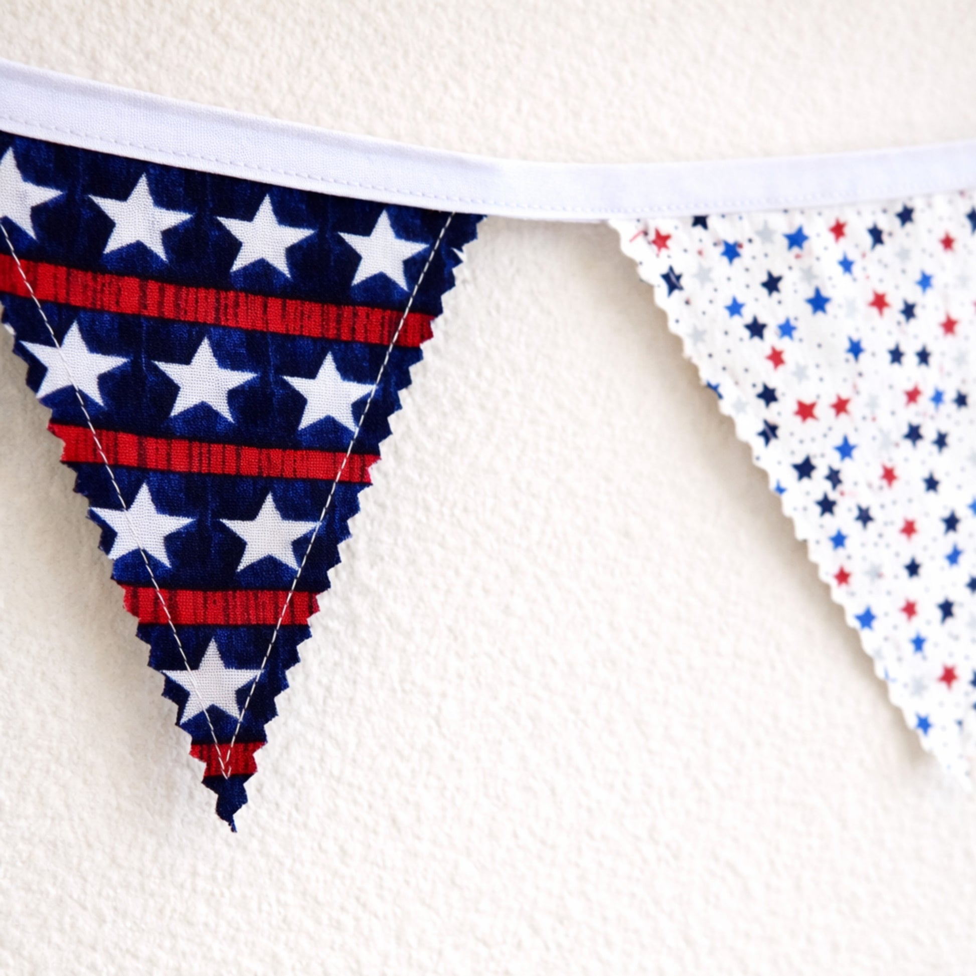 Close up of patriotic bunting banner showing zig zag pinked fabric edges and star print flags with white binding