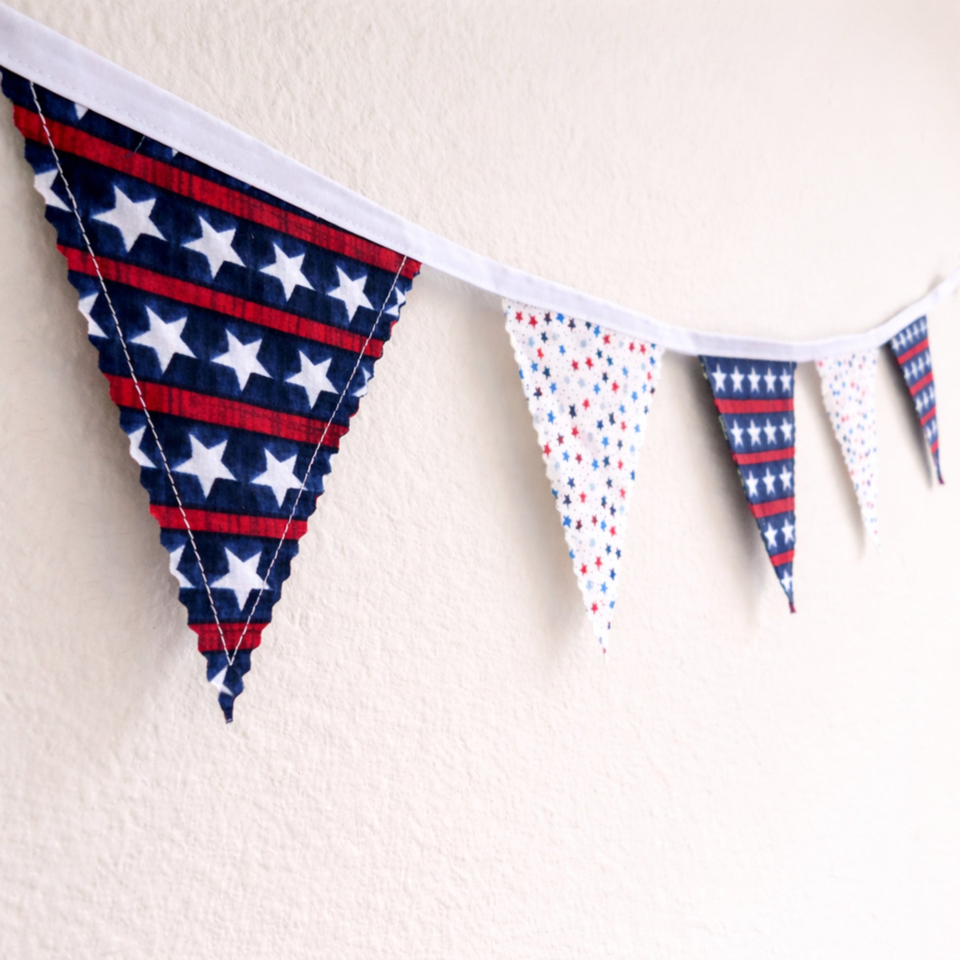 Angled view of handmade patriotic bunting banner with red white and blue star fabric flags and white binding