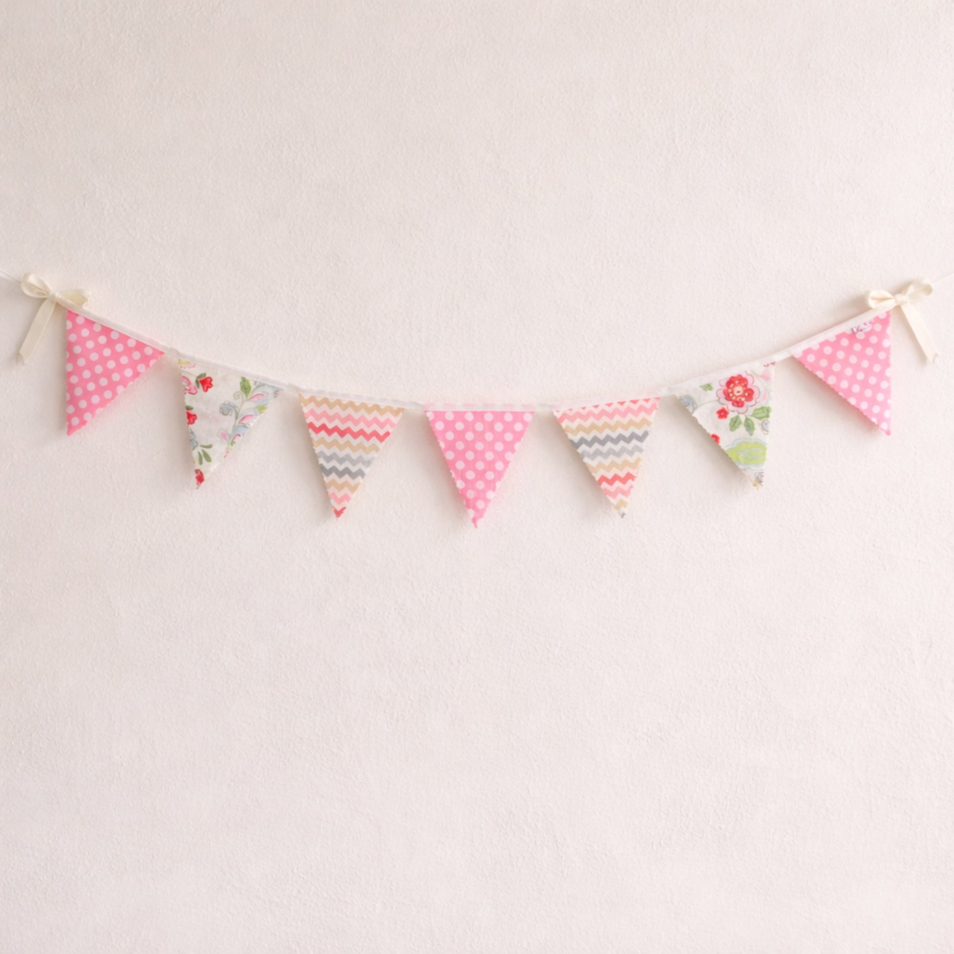 Pink floral and chevron bunting flags with polka dot accents and cream ribbon bows, nursery wall decor banner