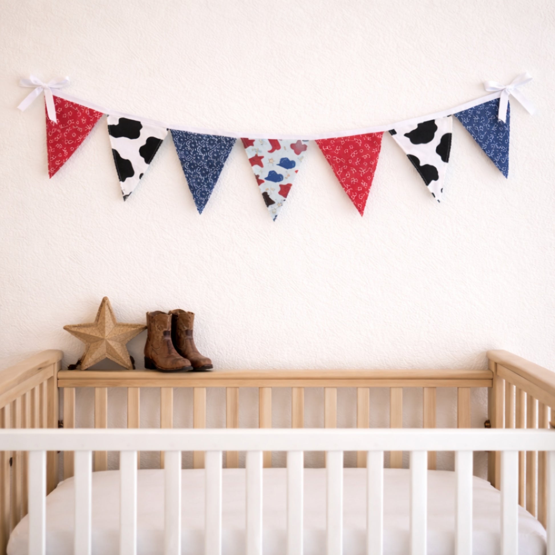 Western themed fabric bunting banner hanging above baby crib with cowboy boots nursery decor