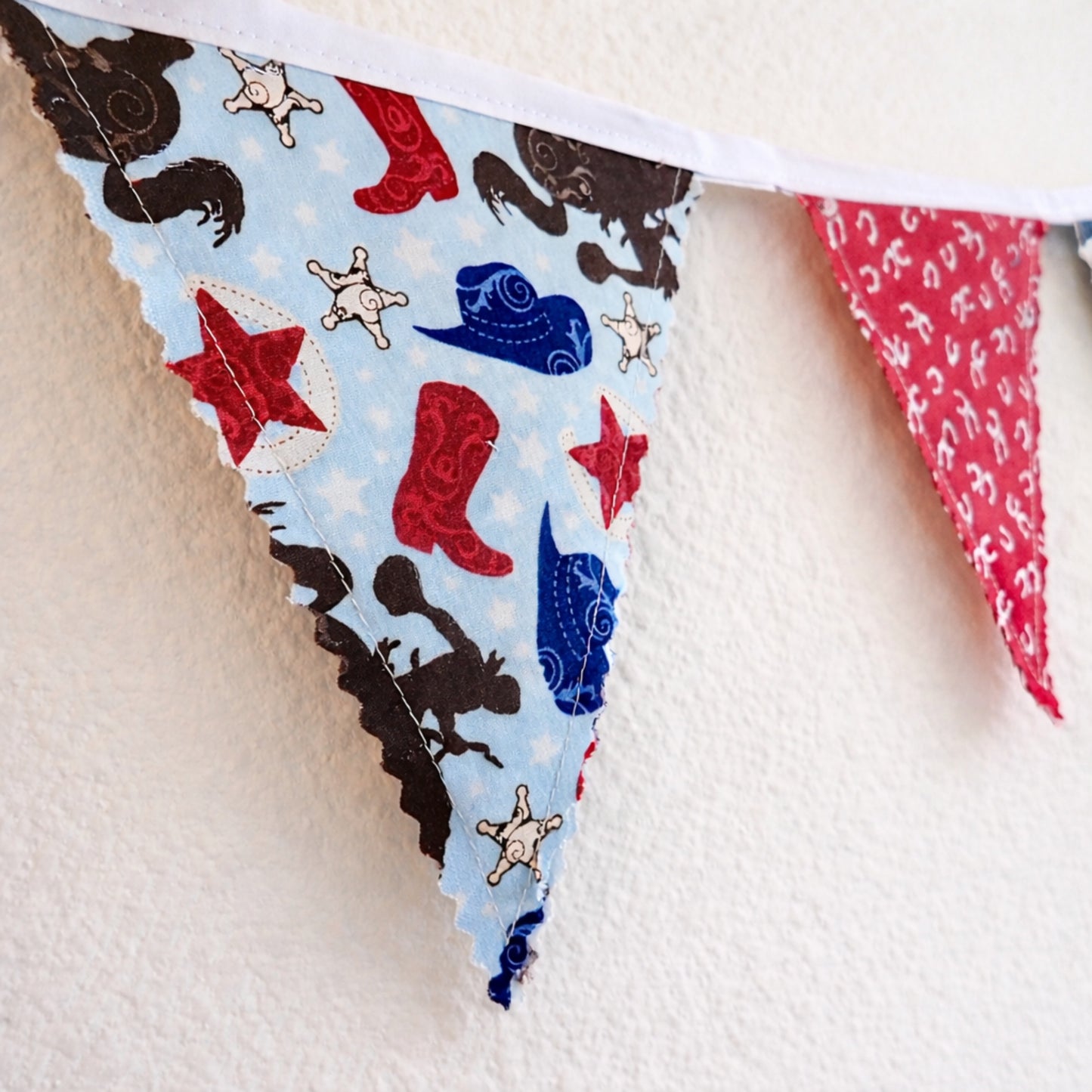 Close up of handmade western fabric bunting banner showing zigzag pinked edges and cowboy themed fabric