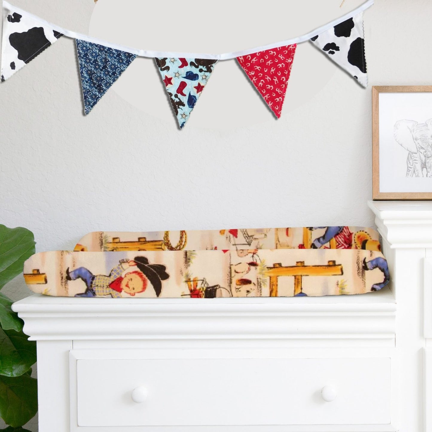 Western-inspired fabric bunting flag banner styled in a neutral nursery above a white dresser