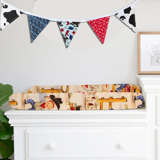 Western-inspired fabric bunting flag banner styled in a neutral nursery above a white dresser