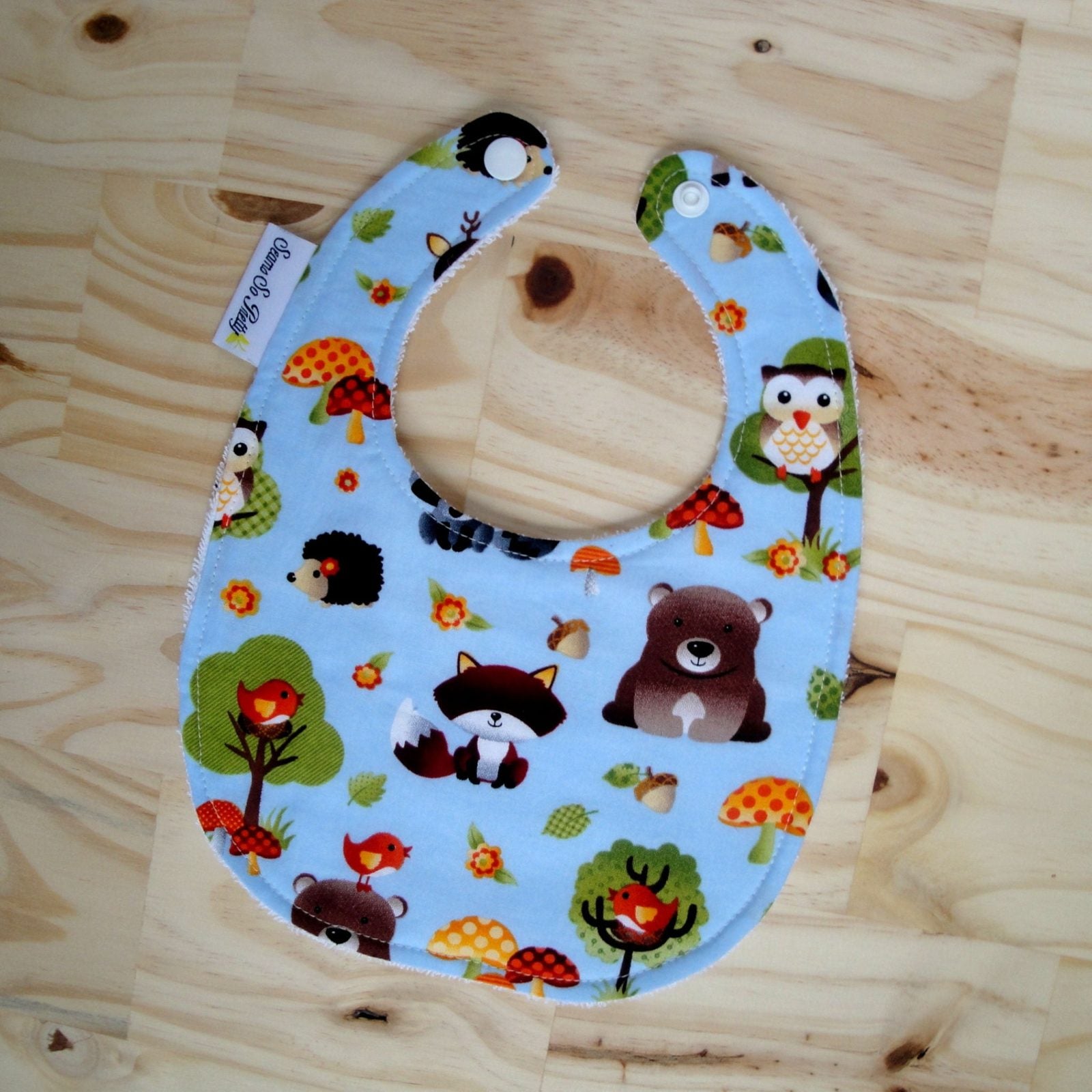 Baby bib  with animal-themed blue fabric cover on a wooden surface