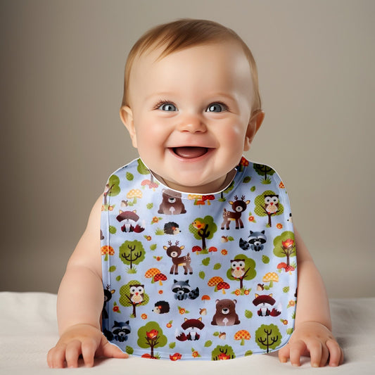 Baby wearing a bib with animal patterns on a plain background