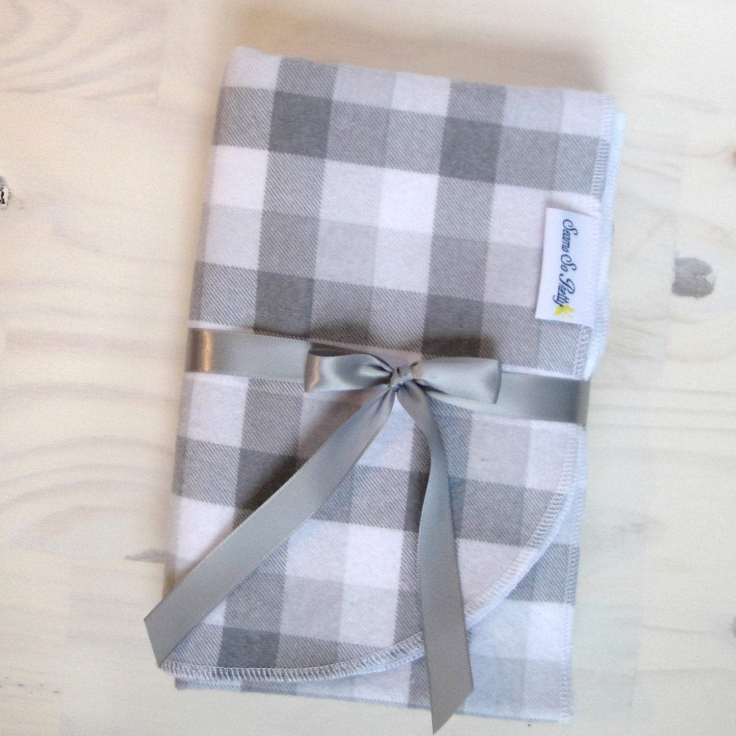 Gray and White Buffalo Check Flannel Blanket Folded with gray ribbon bow