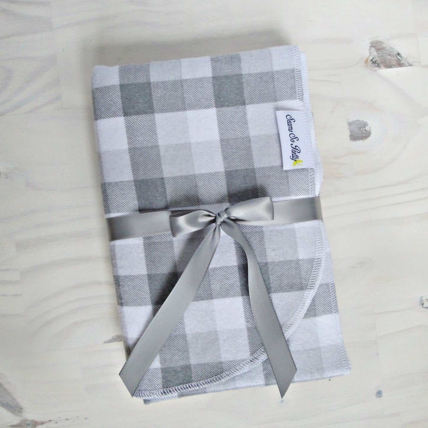 Gray and White Buffalo Check Flannel Blanket Folded with gray ribbon bow